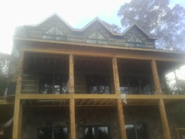 Dormers and porch framing on a large log home under construction — Roof Coating work by our crew in Center Point