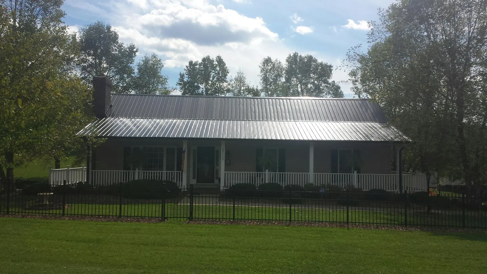 Gray metal roof on a brick ranch with a full width front porch — Gutter Guard Installation work by our crew in Center Point