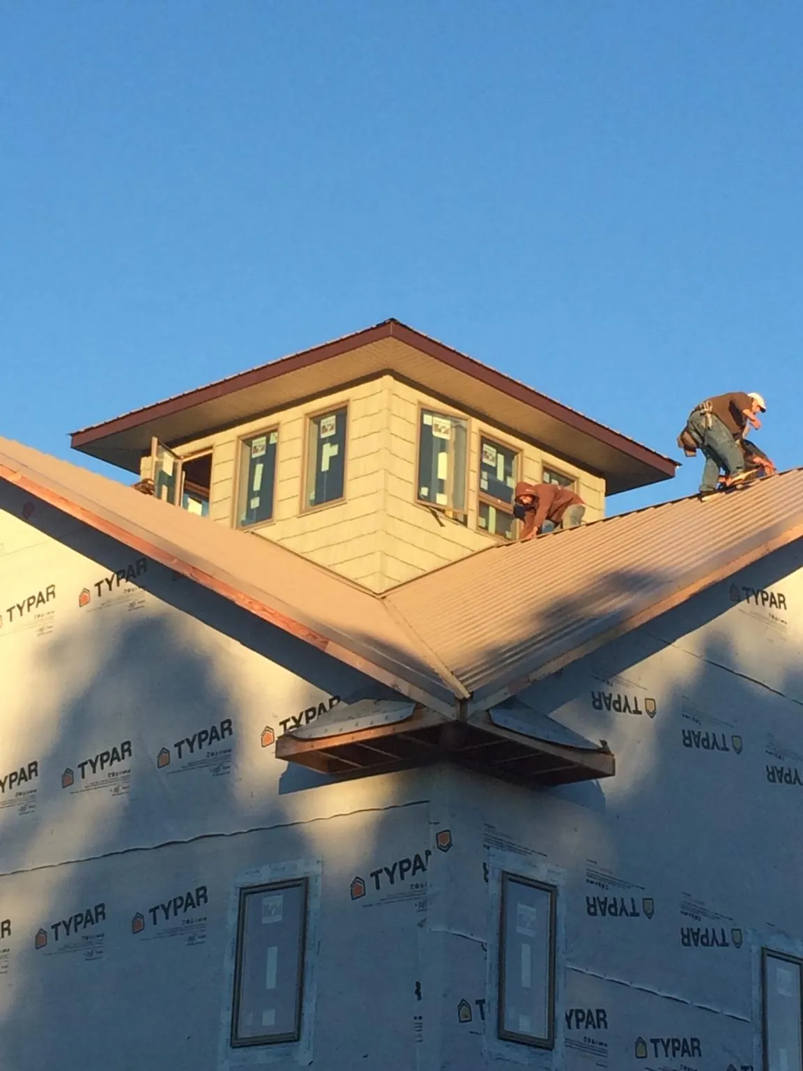 Roofers working around a rooftop cupola on a new metal roof at sunset — Roof Waterproofing in Center Point by Roofing Brothers
